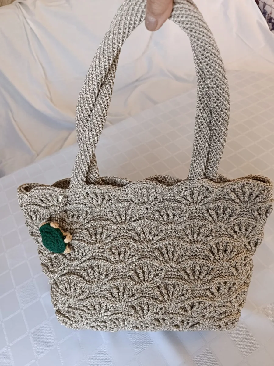 Beige shell-stitch bag held over a bed